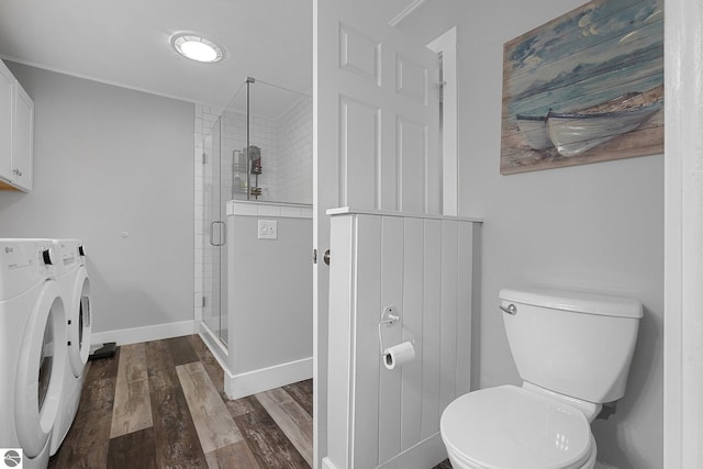 bathroom featuring separate washer and dryer, toilet, baseboards, wood finished floors, and a stall shower