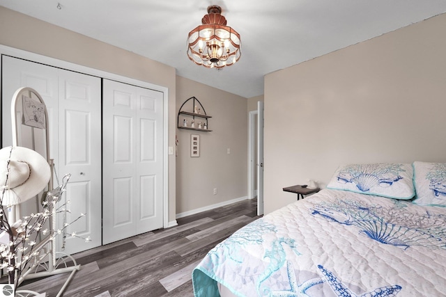 bedroom with baseboards, a closet, wood finished floors, and a chandelier