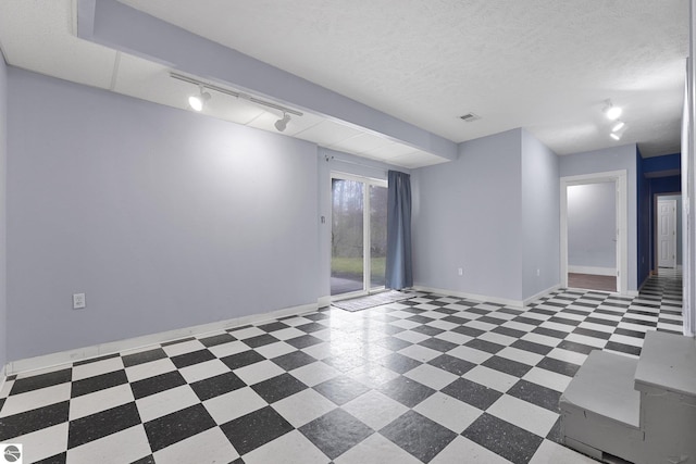 unfurnished room with tile patterned floors, visible vents, track lighting, and baseboards