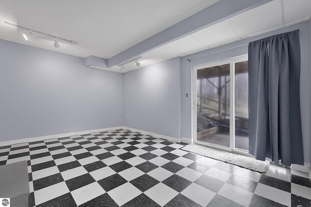 unfurnished room featuring tile patterned floors, track lighting, and baseboards