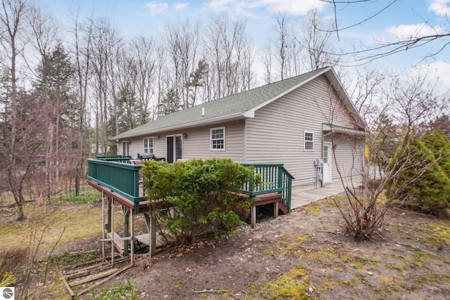 back of property with roof with shingles and a deck