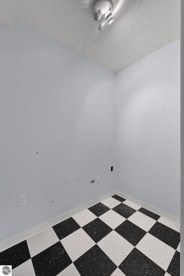 empty room with a textured ceiling and tile patterned floors