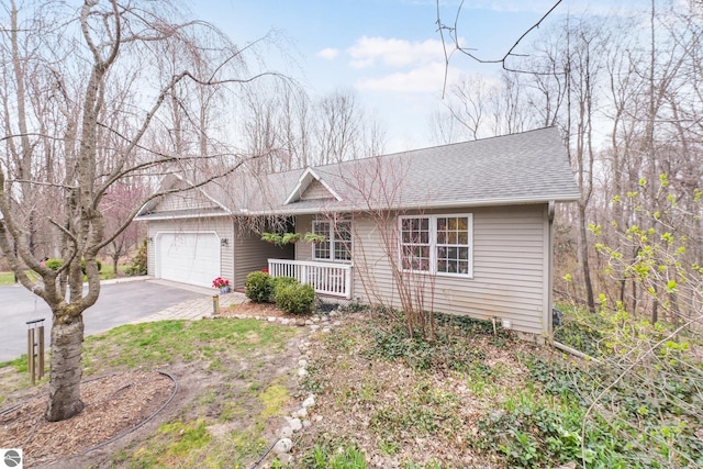 single story home featuring an attached garage, a shingled roof, aphalt driveway, and covered porch