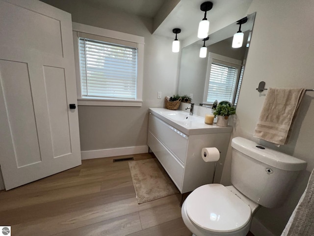 bathroom with visible vents, wood finished floors, baseboards, vanity, and toilet