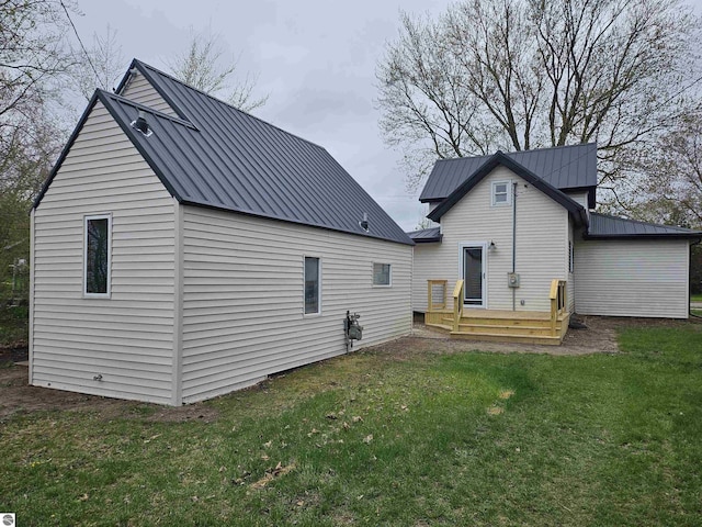 rear view of house with a yard, a standing seam roof, and metal roof