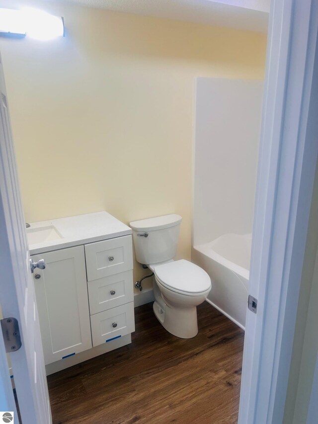 bathroom with vanity, a bathing tub, toilet, and wood finished floors