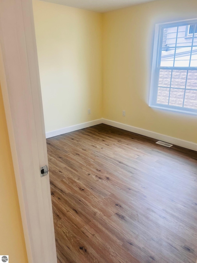 unfurnished room with visible vents, baseboards, and dark wood-type flooring