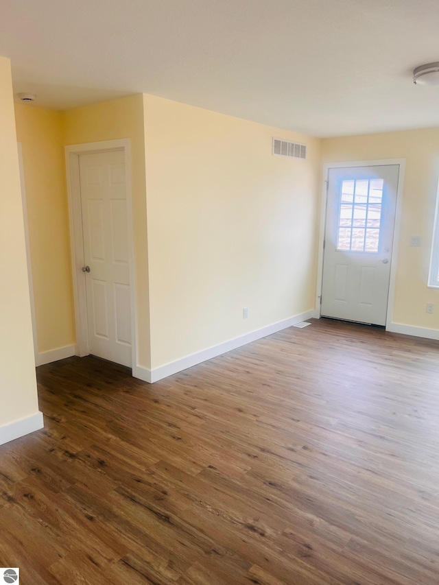 unfurnished room with baseboards, dark wood-type flooring, and visible vents