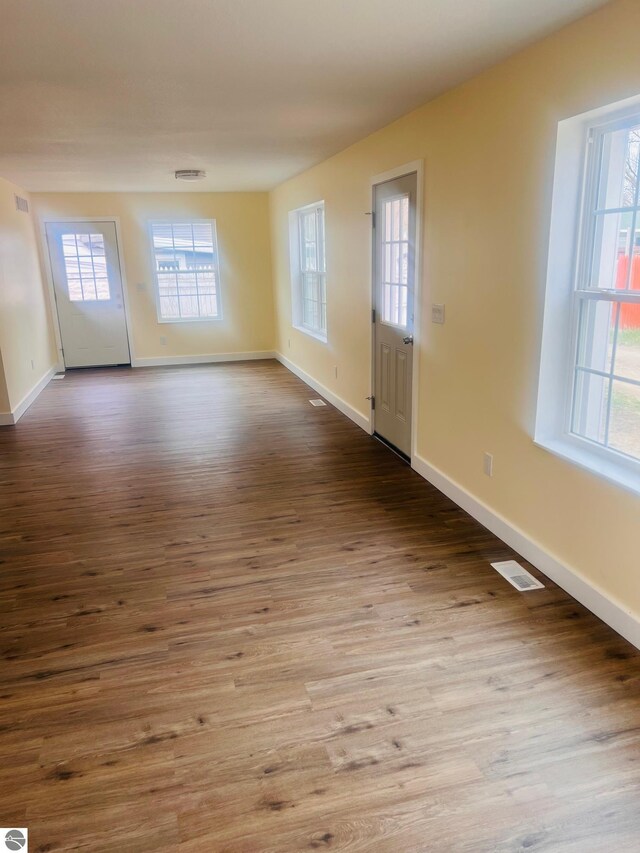 empty room with baseboards, wood finished floors, and visible vents