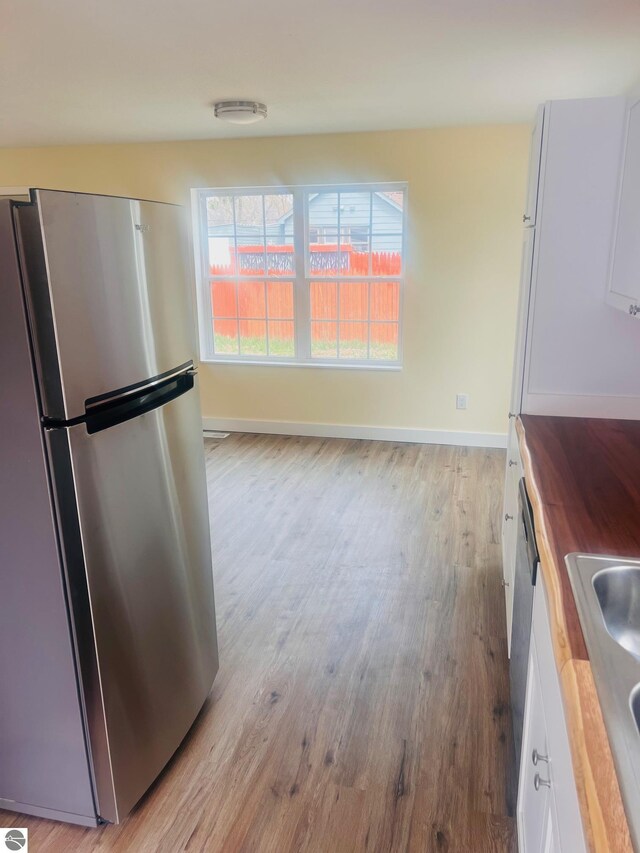 unfurnished dining area featuring a sink, baseboards, and light wood-style flooring