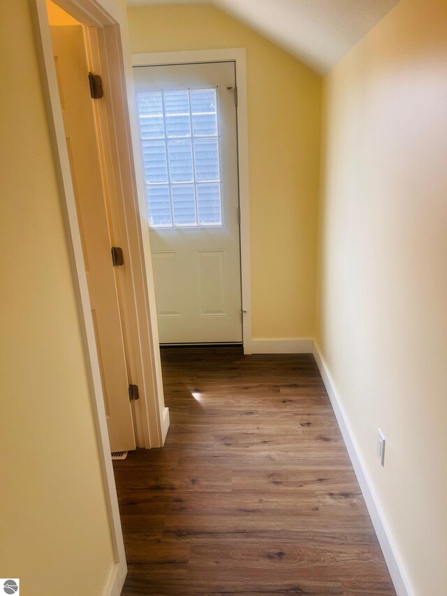 corridor with baseboards, vaulted ceiling, and wood finished floors