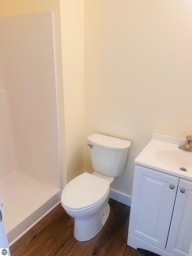 full bath with baseboards, a shower stall, toilet, and wood finished floors