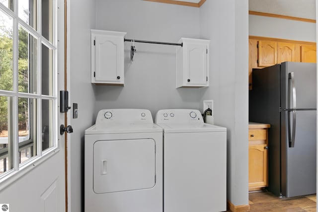 laundry room featuring separate washer and dryer, ornamental molding, cabinet space, and light wood-type flooring