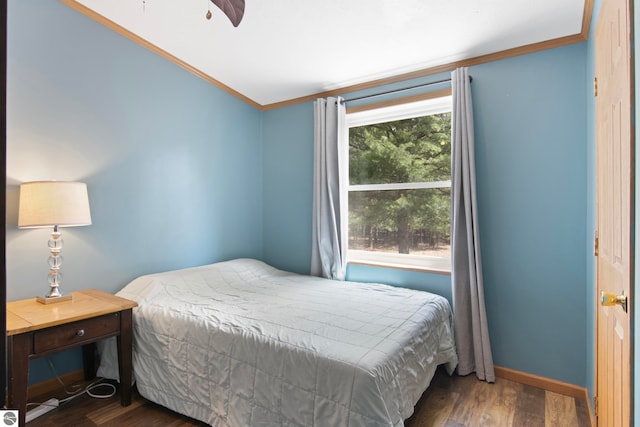 bedroom with crown molding, baseboards, and wood finished floors