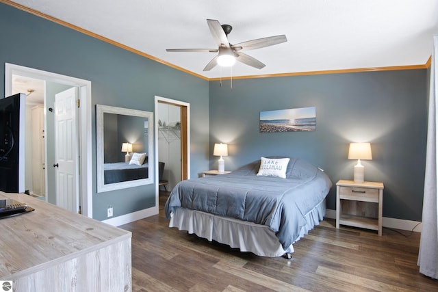 bedroom featuring crown molding, baseboards, wood finished floors, a spacious closet, and a closet