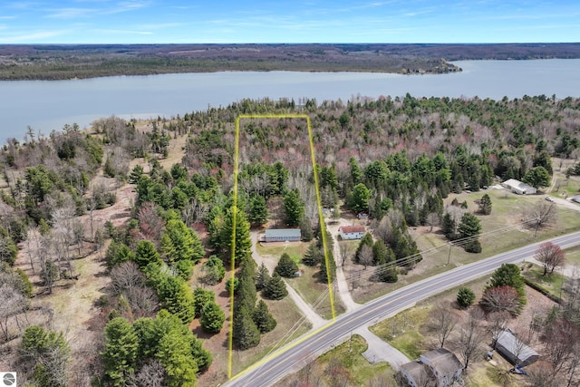 birds eye view of property featuring a water view and a wooded view