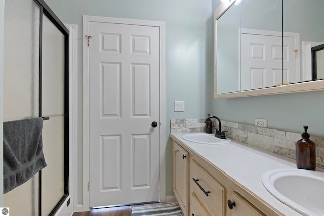 bathroom featuring double vanity, a shower stall, and a sink