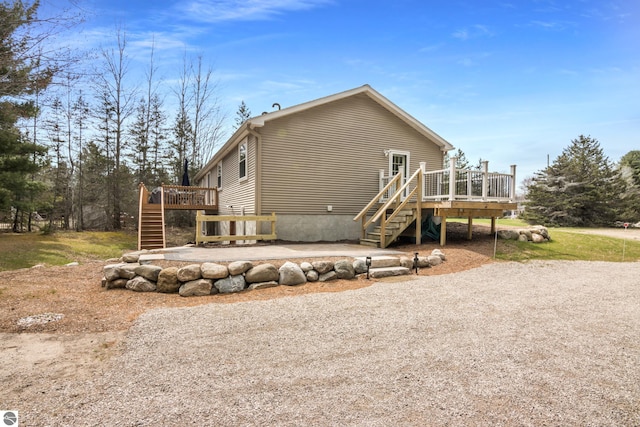 view of property exterior with stairway, a wooden deck, and a patio area