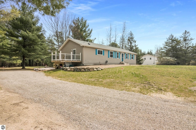 manufactured / mobile home with a deck, gravel driveway, and a front lawn