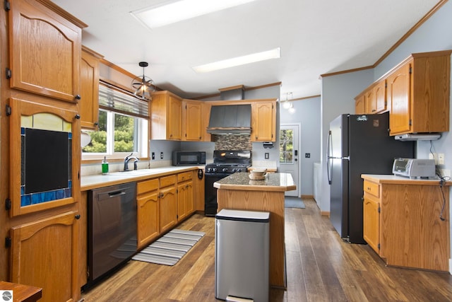 kitchen featuring decorative backsplash, a center island, a sink, black appliances, and ornamental molding