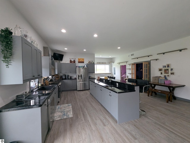 kitchen featuring a center island, appliances with stainless steel finishes, dark countertops, and a kitchen breakfast bar