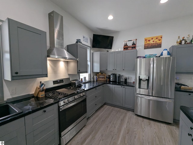 kitchen with gray cabinets, light wood finished floors, stainless steel appliances, recessed lighting, and wall chimney exhaust hood