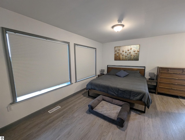 bedroom with visible vents, baseboards, and wood finished floors