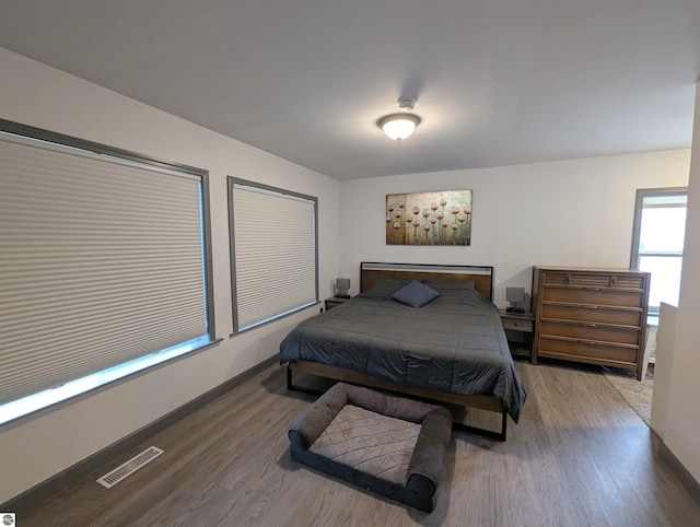 bedroom featuring baseboards, wood finished floors, and visible vents