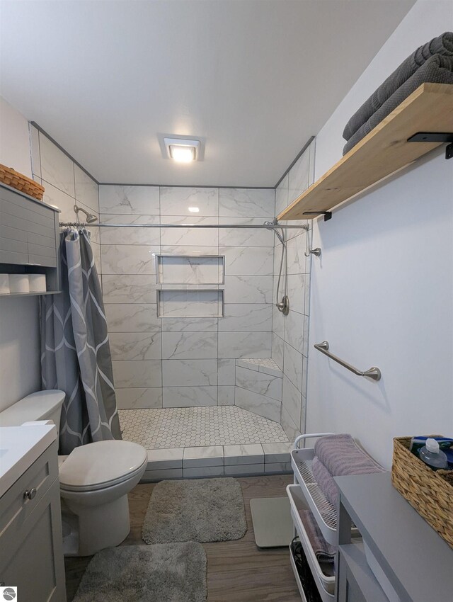 bathroom featuring toilet, a shower stall, wood finished floors, and vanity