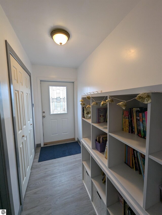 doorway to outside featuring baseboards and wood finished floors