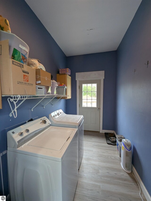washroom featuring separate washer and dryer, laundry area, light wood-style floors, and baseboards
