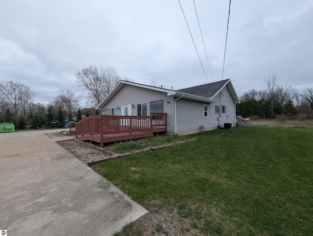 view of side of property featuring a yard, central AC, and a wooden deck