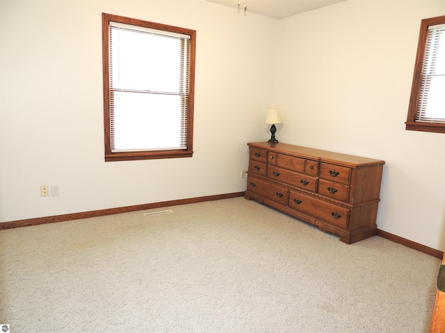 bedroom featuring baseboards, visible vents, and light colored carpet