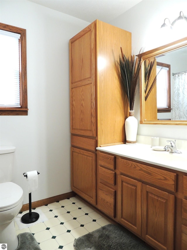 full bathroom with baseboards, toilet, and vanity