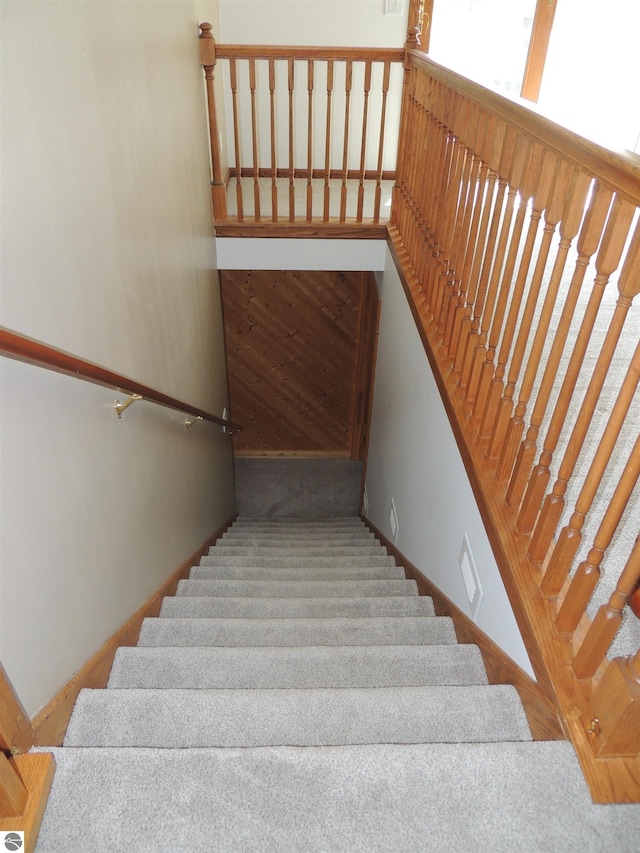 stairway featuring baseboards and carpet flooring