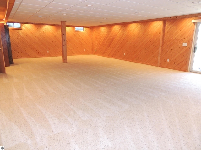 basement with carpet flooring, wood walls, and a paneled ceiling