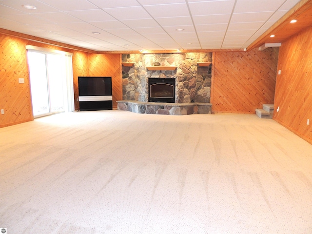 unfurnished living room featuring carpet floors, recessed lighting, wooden walls, and a fireplace