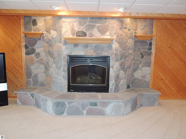 room details with carpet floors, wood walls, a paneled ceiling, and a fireplace