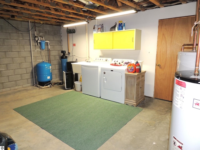 laundry area featuring laundry area, water heater, washing machine and dryer, and concrete block wall