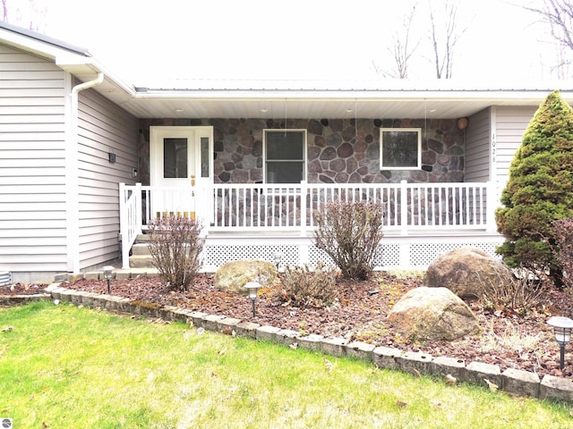 entrance to property with a porch and stone siding