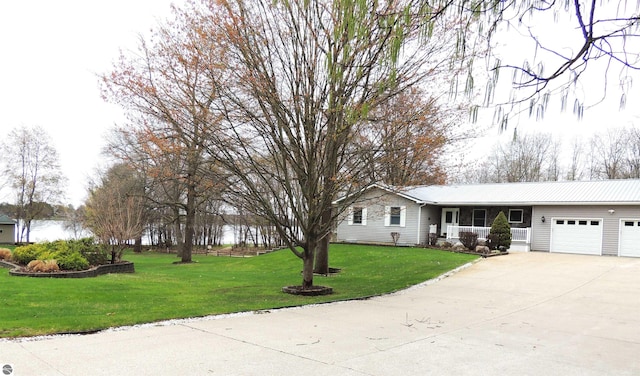 single story home featuring concrete driveway, a front yard, metal roof, an attached garage, and a porch