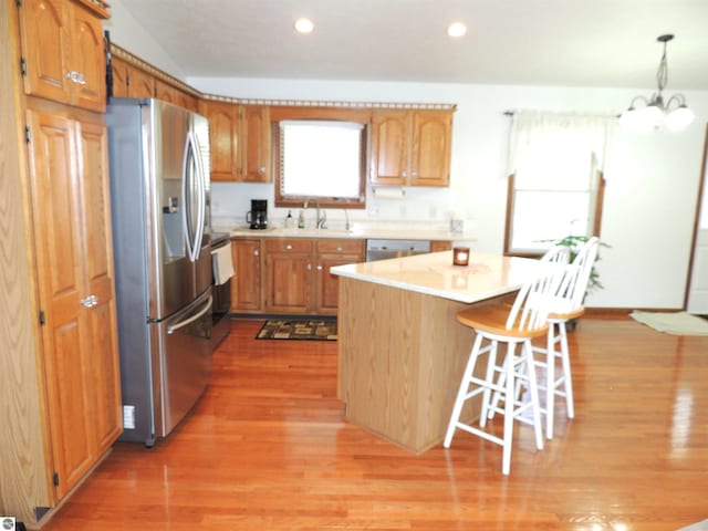 kitchen with a breakfast bar area, a kitchen island, appliances with stainless steel finishes, light wood-type flooring, and light countertops