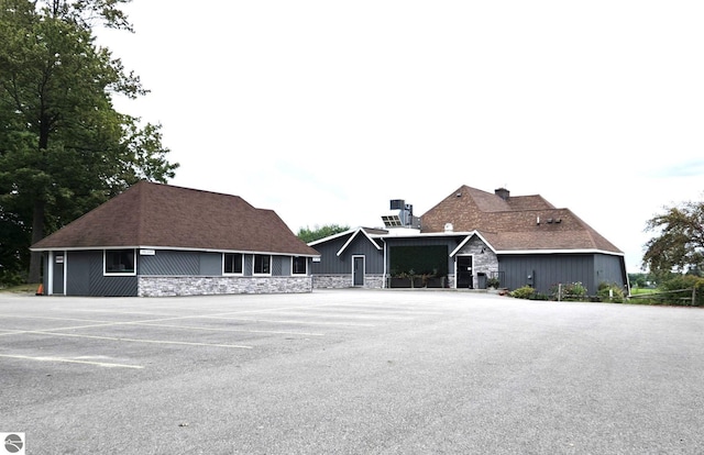 view of front facade featuring uncovered parking and stone siding
