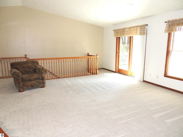 unfurnished room featuring a healthy amount of sunlight, carpet flooring, and an upstairs landing