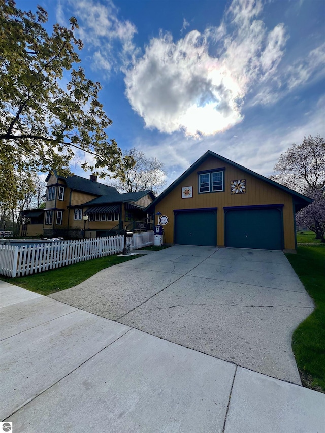 view of front facade featuring an attached garage, concrete driveway, and fence private yard