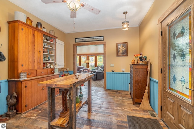interior space featuring ceiling fan, visible vents, crown molding, light wood-type flooring, and a wainscoted wall