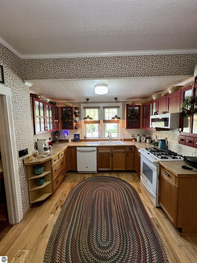 kitchen featuring open shelves, a sink, light wood-style floors, ornamental molding, and white appliances