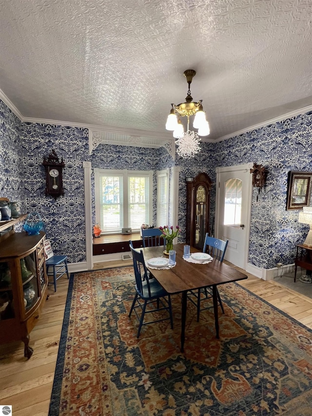 dining room with crown molding, baseboards, light wood finished floors, an inviting chandelier, and wallpapered walls