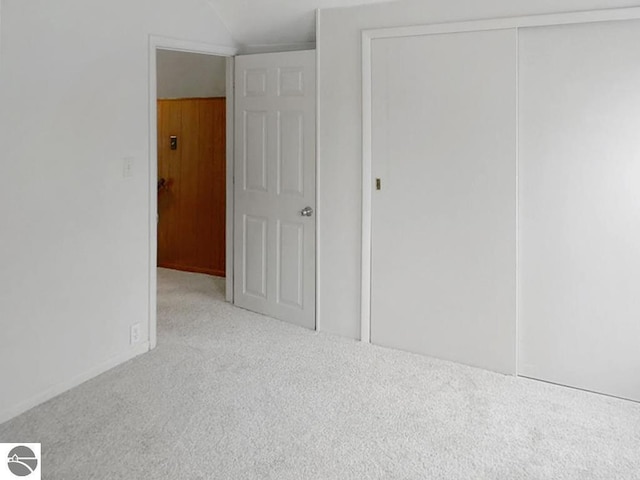 unfurnished bedroom featuring carpet floors, lofted ceiling, and a closet