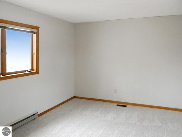 carpeted spare room featuring baseboards, a baseboard heating unit, and visible vents